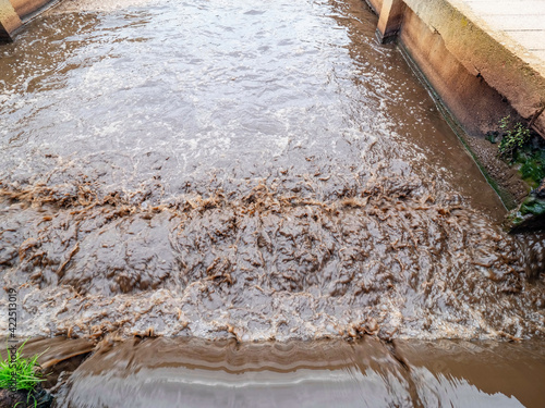 Foamy river sewage with concentrated biomass. Brown sludge water in channel