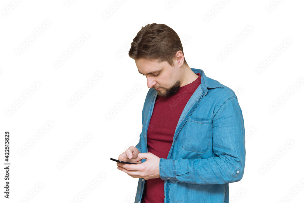 a young attractive man with a beard looks at a smartphone mobile phone, communicates with social networks, plays mobile games on a white isolated background a young attractive man with a beard looks at a smartphone mobile phone, communicates with social networks, plays mobile games on a white isolated background