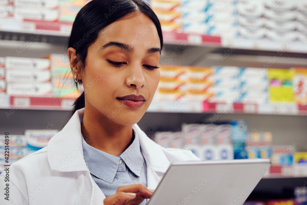 Portrait of young woman in labcoat using digital tablet in pharmacy Portrait of young woman in labcoat using digital tablet in pharmacy