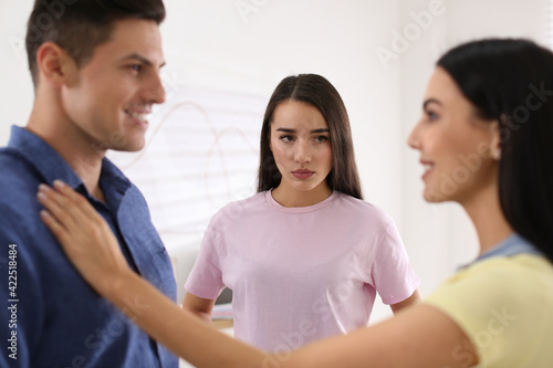 Fotografie Unhappy woman feeling jealous while couple spending time together indoors