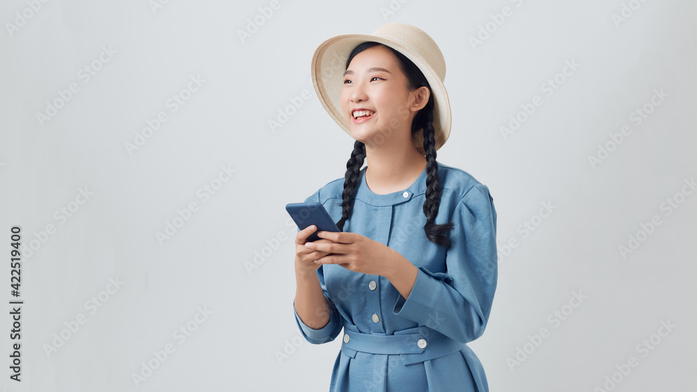 Cheerful young pretty woman standing isolated over gray background, using mobile phone Cheerful young pretty woman standing isolated over gray background, using mobile phone