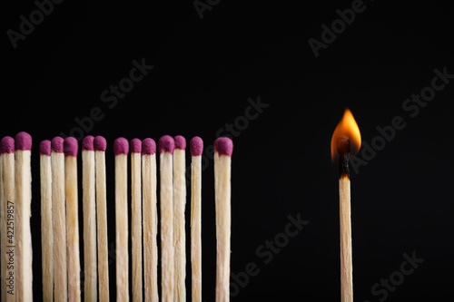 Burning match among others on black background