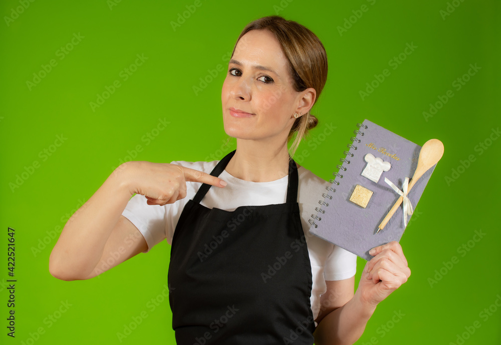 Young caucasian woman holding kitchen book against green background Young caucasian woman holding kitchen book against green background