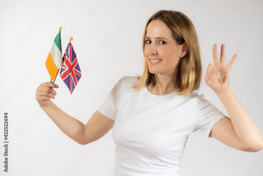 Portrait of a smiling casual young woman holding british and irish flags isolated over white background Portrait of a smiling casual young woman holding british and irish flags isolated over white background