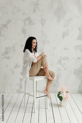 model shooting in the studio girl sitting on a white chair with a bouquet of flowers