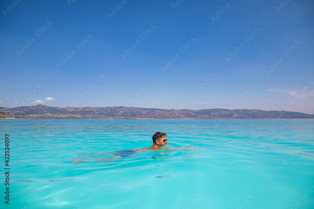Man is swimming in turquoise crater lake Salda Golu, Turkey