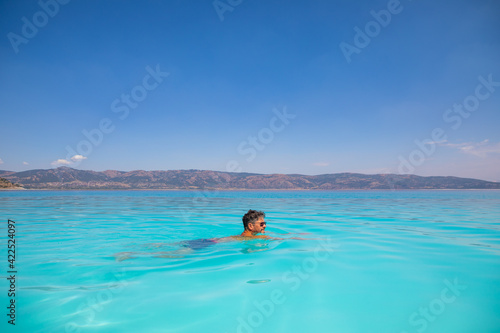 Man is swimming in turquoise crater lake Salda Golu, Turkey © dtatiana