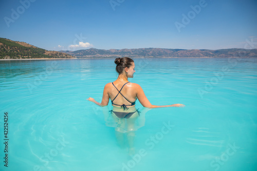 A young sexy female in swim suit is swimming in turquoise crater lake Salda Golu  Turkey