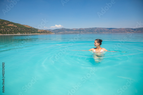 A young sexy female in swim suit is swimming in turquoise crater lake Salda Golu, Turkey © dtatiana