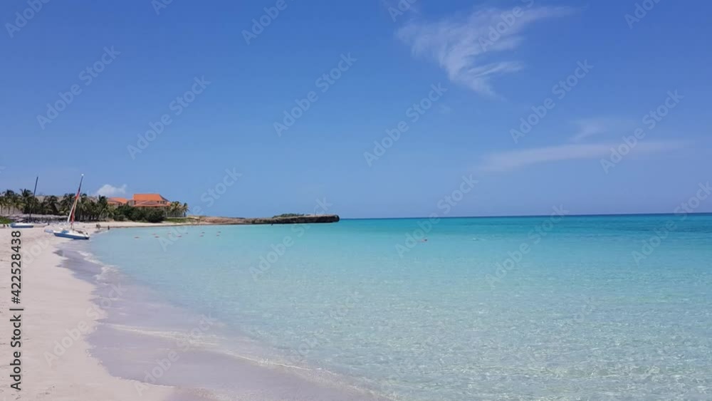 Beautiful tropical beach on a sunny day with blue sky and light waves rolling on the white sand. Beautiful tropical beach on a sunny day with blue sky and light waves rolling on the white sand.