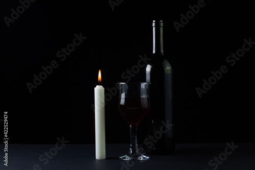 Wine and candle on a dark background. Creative photo of red wine on a black background. Wine by candlelight