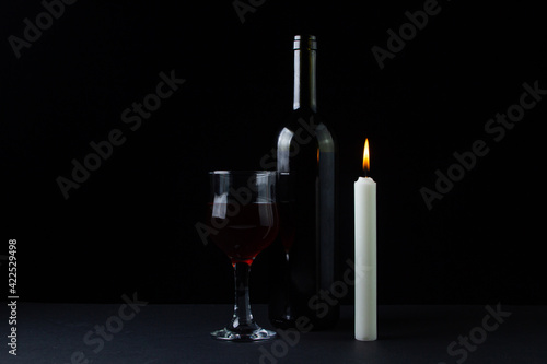 Wine and candle on a dark background. Creative photo of red wine on a black background. Wine by candlelight