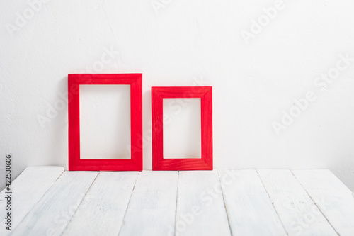 pair of empty red picture frames on white wooden table © tstock