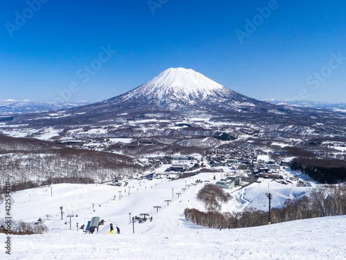 Looking at snowy volcano and quiet ski resort on a clear day in early spring (Niseko Mt.Resort Grand Hirafu, Hokkaido, Japan) photo