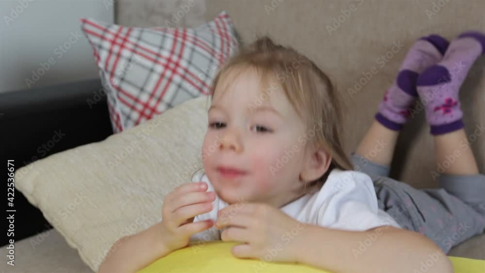 a large portrait of a little girl lying on a yellow pillow opens her mouth wide and shows her tongue. a large portrait of a little girl lying on a yellow pillow opens her mouth wide and shows her tongue.