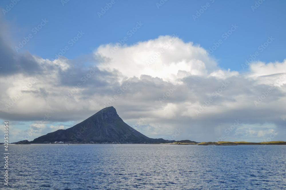 View from ferry to the Lovund island in Helgeland archipelago, Norwegian sea on sunny summer morning. White clouds over the blue sea