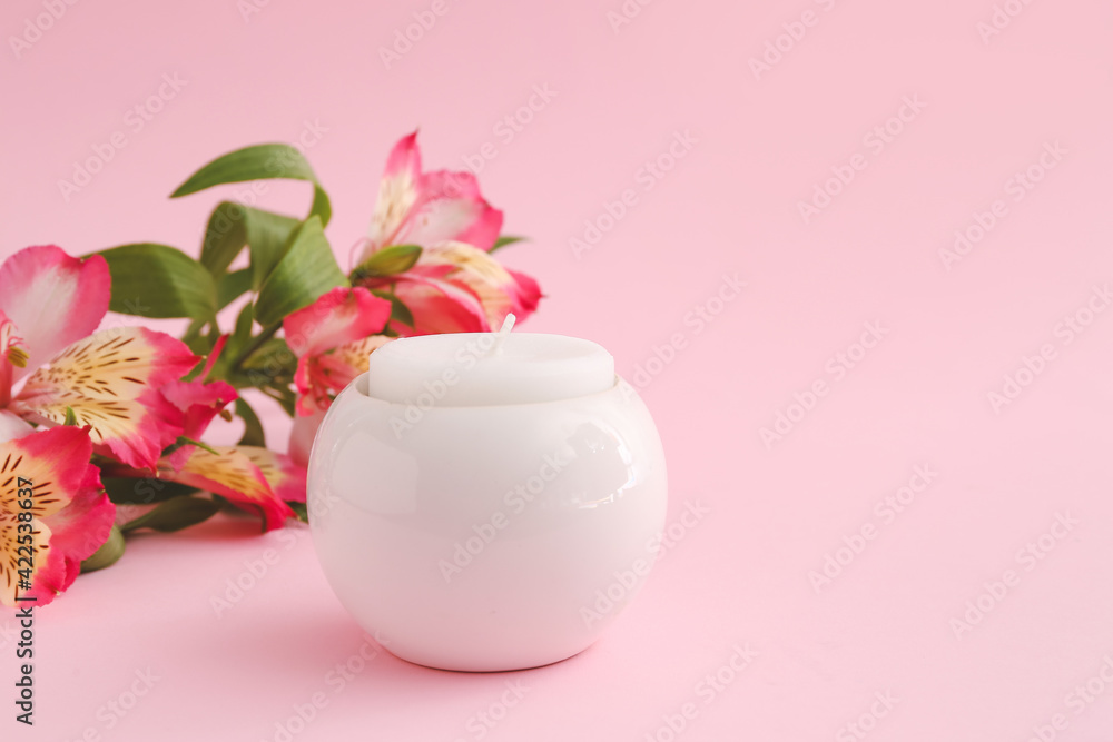 Candle in holder and flowers on color background