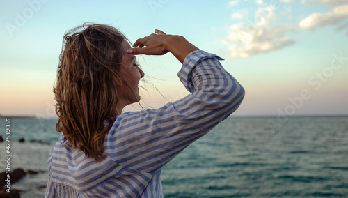 Woman enjoying freedom. Standing at the edge of the sea looks at the horizon