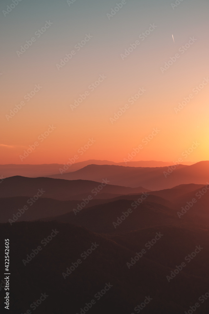 A vibrant orange, yellow, blue sunset over the layers of the Appalachian Mountain range from Shenandoah National Park, Virginia, USA.