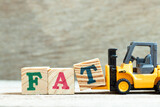 Toy forklift hold letter block T to complete word FAT (Obesity or abbreviation of factory acceptance test, file allocation table) on wood background
