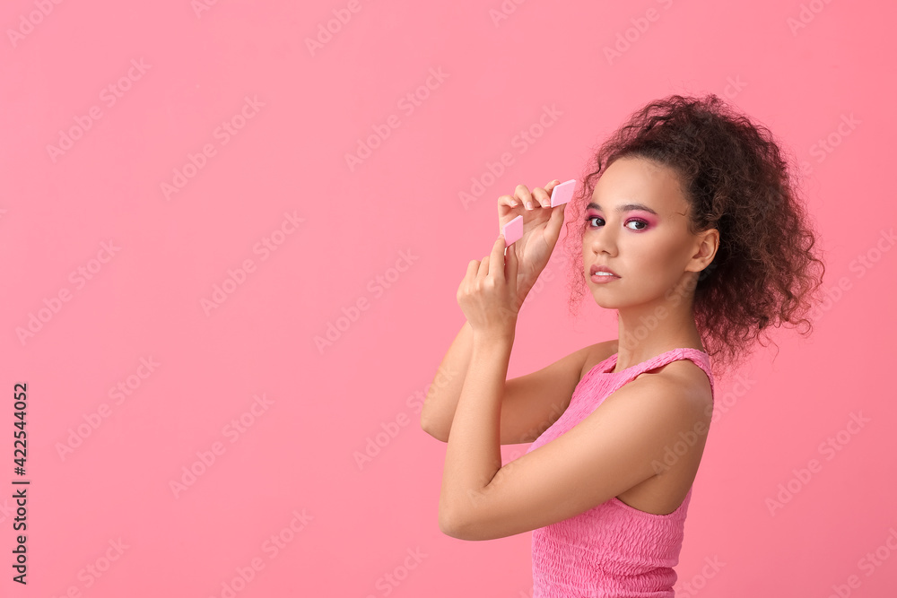 Beautiful young African-American woman with makeup sponges on color background Beautiful young African-American woman with makeup sponges on color background