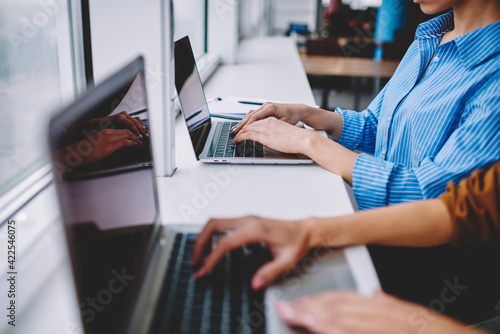 Cropped female coworkers using laptop computers for sharing media content during remote brainstorming working, bloggers searching website for browsing wireless publication and watching video © BullRun