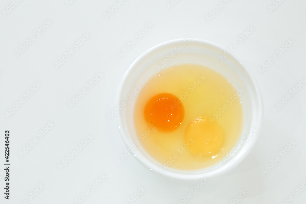 raw broken chicken eggs. egg yolks in a white plate raw broken chicken eggs. egg yolks in a white plate