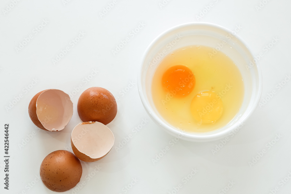 raw broken chicken eggs and broken shells. egg yolks in a white plate raw broken chicken eggs and broken shells. egg yolks in a white plate