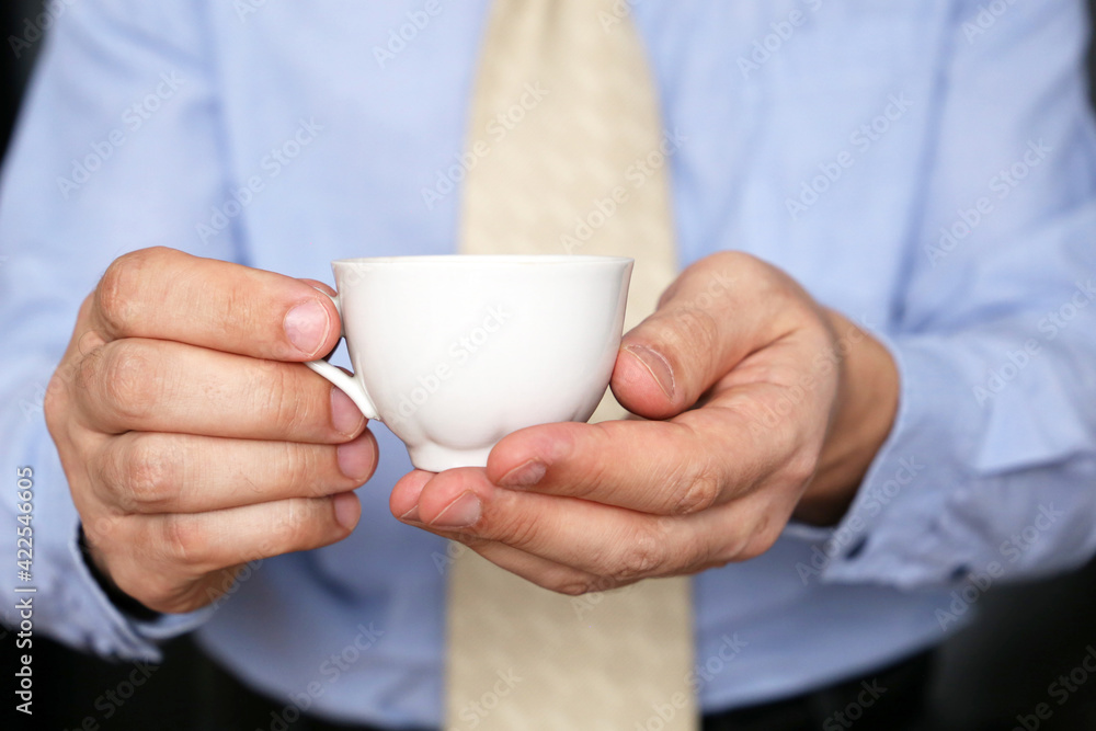 Man in office clothes with coffee. White cup of hot drink in male hands, break during work in office Man in office clothes with coffee. White cup of hot drink in male hands, break during work in office