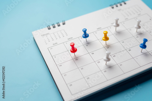 Calendar on solid ิblue background with copy space, pinned in a calender on datebusiness meeting schedule, travel planning or project milestone and reminder concept. photo