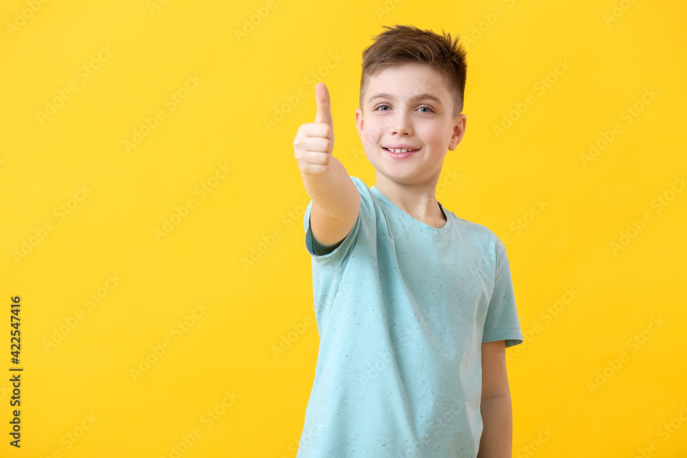 Happy little boy showing thumb-up gesture on color background Happy little boy showing thumb-up gesture on color background