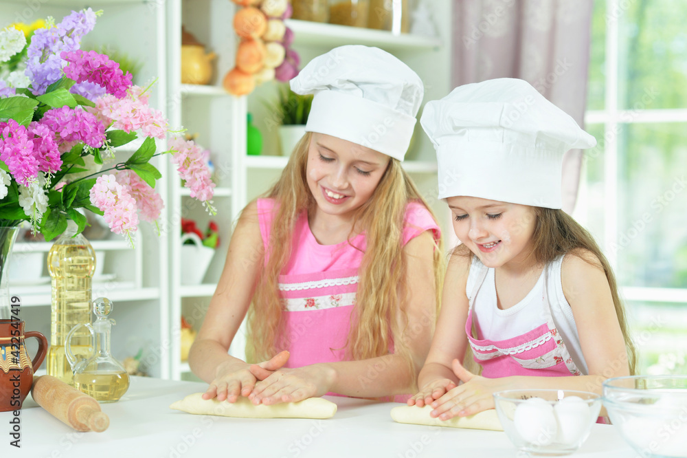 Cute little girls in chefs hats making dough Cute little girls in chefs hats making dough