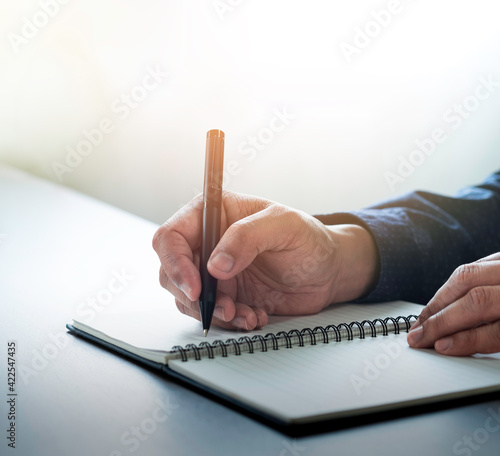 Close-up of man hand using writing pen memo on notebook paper or letter, diary on table desk office. Workplace for student, writer with copy space. business working and learning education concept.