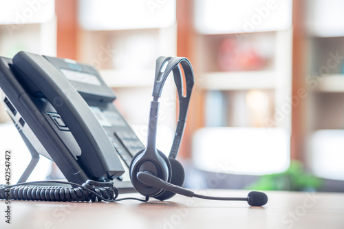 Close up soft focus on headset with telephone devices at office desk for customer service support.VOIP headset for customer service support (call center) concept.