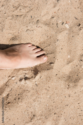 a man's foot on the sand. Summer beach season
