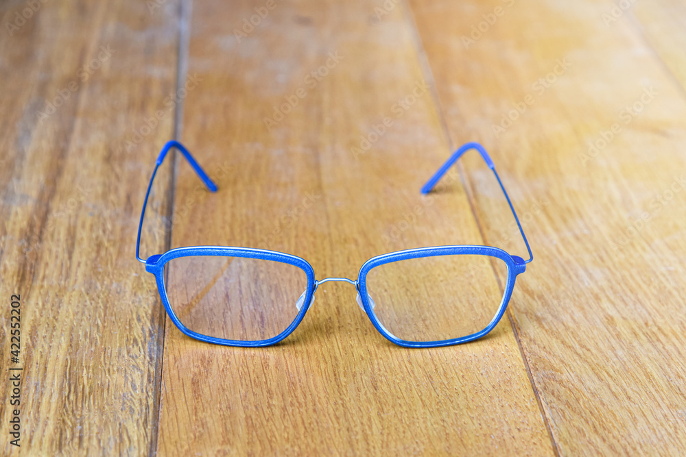Clear eyeglasses, Glasses blue frame with wire strip modern style on wood background Clear eyeglasses, Glasses blue frame with wire strip modern style on wood background