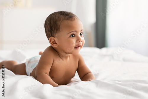 Fotografie, Obraz Curious adorable little African American infant lying on bed