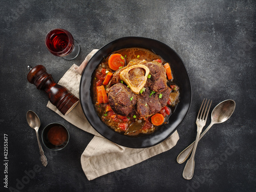 Italian menu: braised veal steak Ossobuco alla Milanese with  vegetable sauce close-up. Beef Leg Slice with marrow.