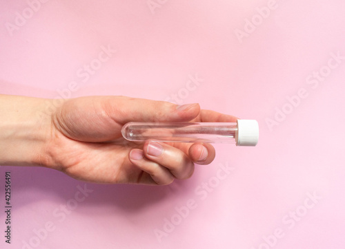 hand with capsule for vaccine on pink background