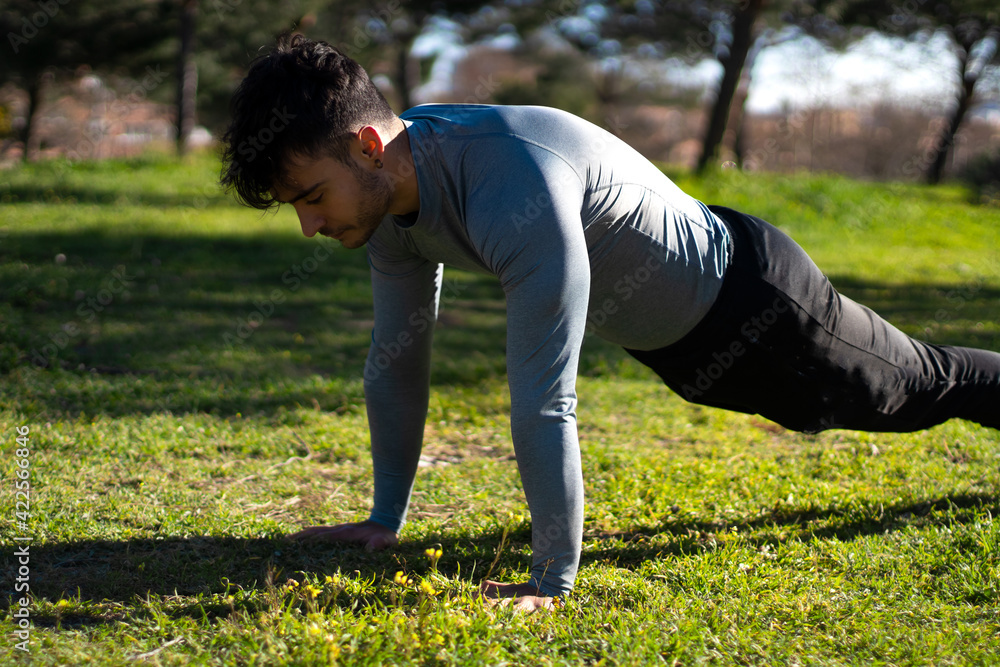 Young and sportive man doing push-ups in a park.workout and health Young and sportive man doing push-ups in a park.workout and health