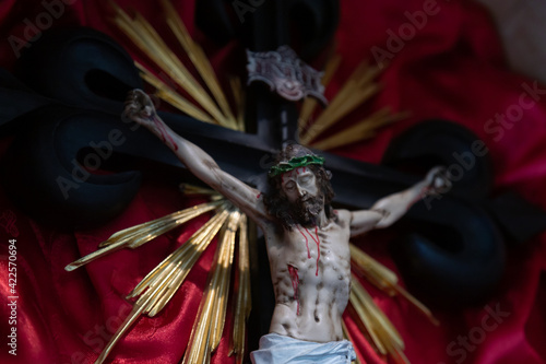 Obraz na płótnie Black crucifix in Santiago style representing the passion of Our Lord Jesus Christ dead on the cross with red silk fabric in the background