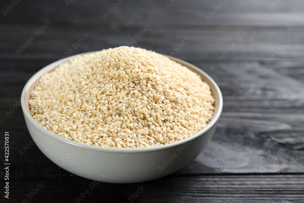 Sesame seeds in bowl on black wooden table Sesame seeds in bowl on black wooden table