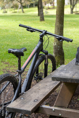 bicycle next to a table and wooden bench outside, healthy activities and means of transport © Alejandro