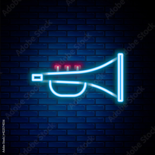Glowing neon line Musical instrument trumpet icon isolated on brick wall background. Colorful outline concept. Vector