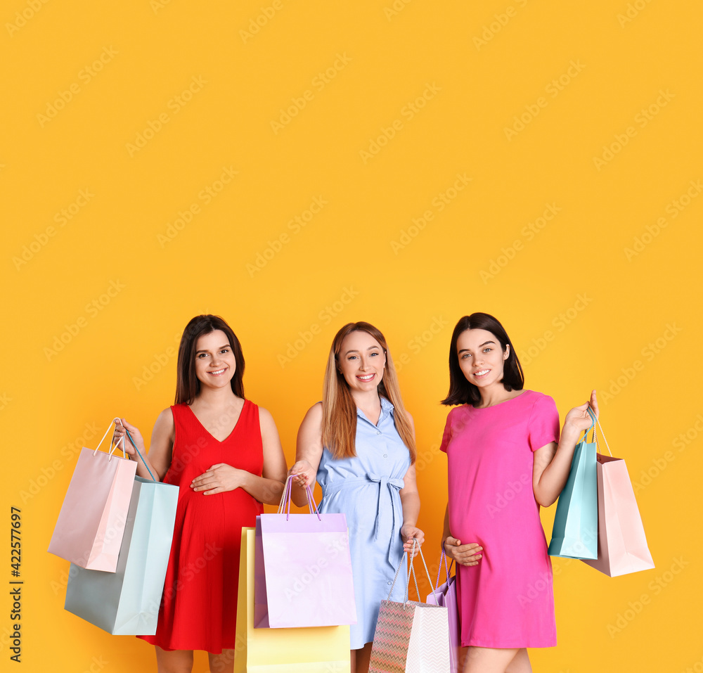 Happy pregnant women with shopping bags on orange background Happy pregnant women with shopping bags on orange background