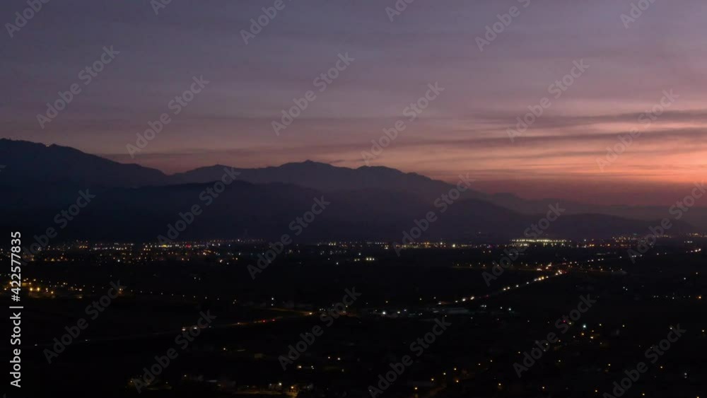 Aerial drone panoramic horizon view of a beautiful scenic mountain landscape and town lights at dusk 