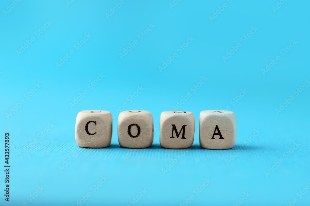 Wooden cubes with word Coma on light blue background, closeup Wooden cubes with word Coma on light blue background, closeup