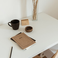 Women's home office workspace. Freelance work, business workplace. Light aesthetic hygge space with wooden chair, table, reed pampas grass bouquet, mug, notebook. Modern interior design.