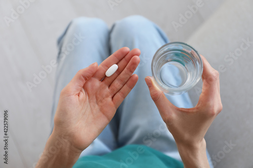 Tableau sur toile Young woman with abortion pill and glass of water, top view