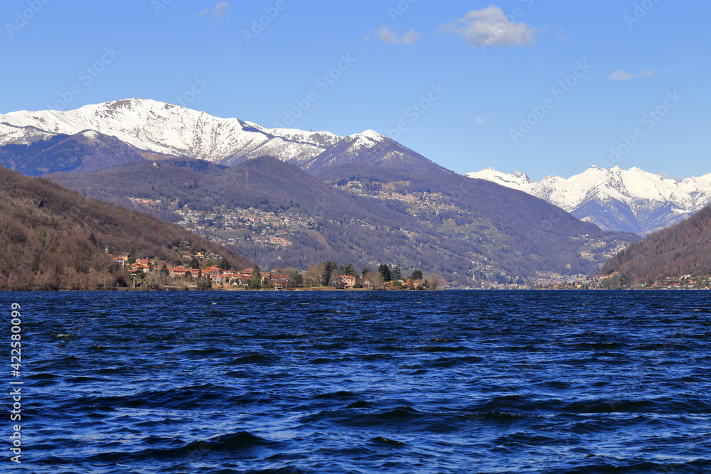 Panorama del lago di Lugano con vento, lago increspato e monti innevati sullo sfondo.